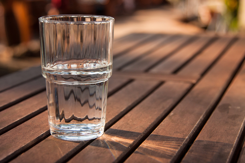 Picture of glass of water on brown wooden picnic table