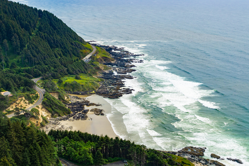 Image looking down at a ocean cove with a highway curving along green cliffs.