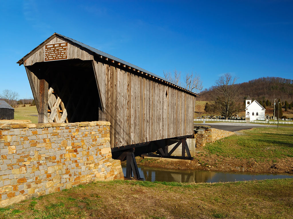 covered bridge with a church in the distance