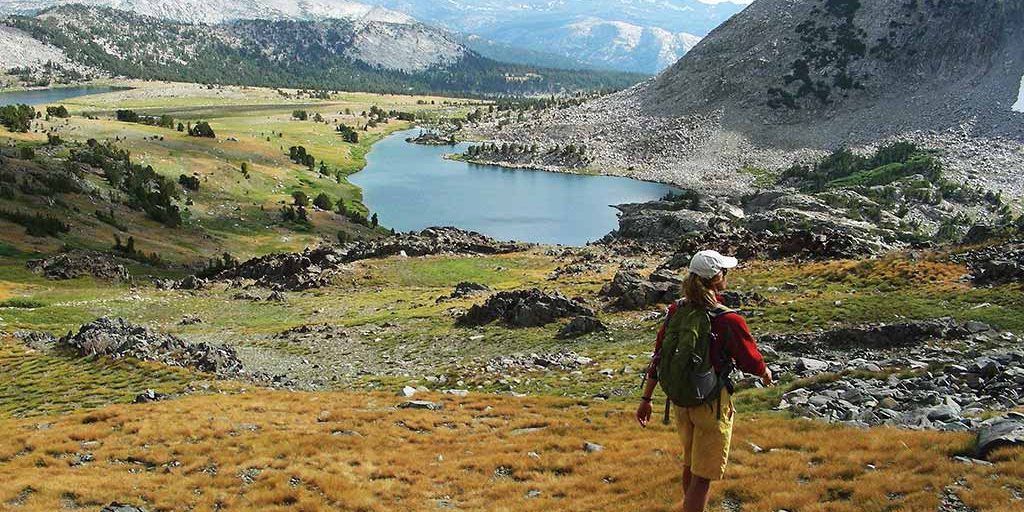 hiker approaching a lake in mountainous landscape