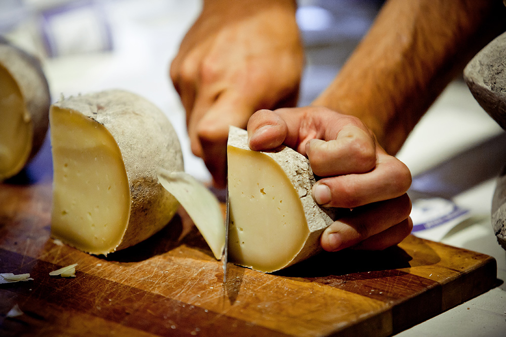 hands holding a knife cutting cheese