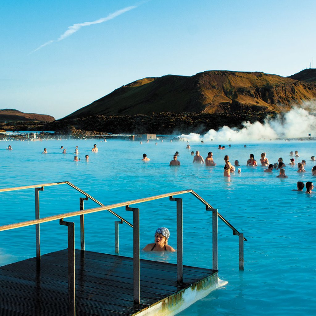 A woman takes a dip in Iceland's Blue Lagoon as others gather nearby