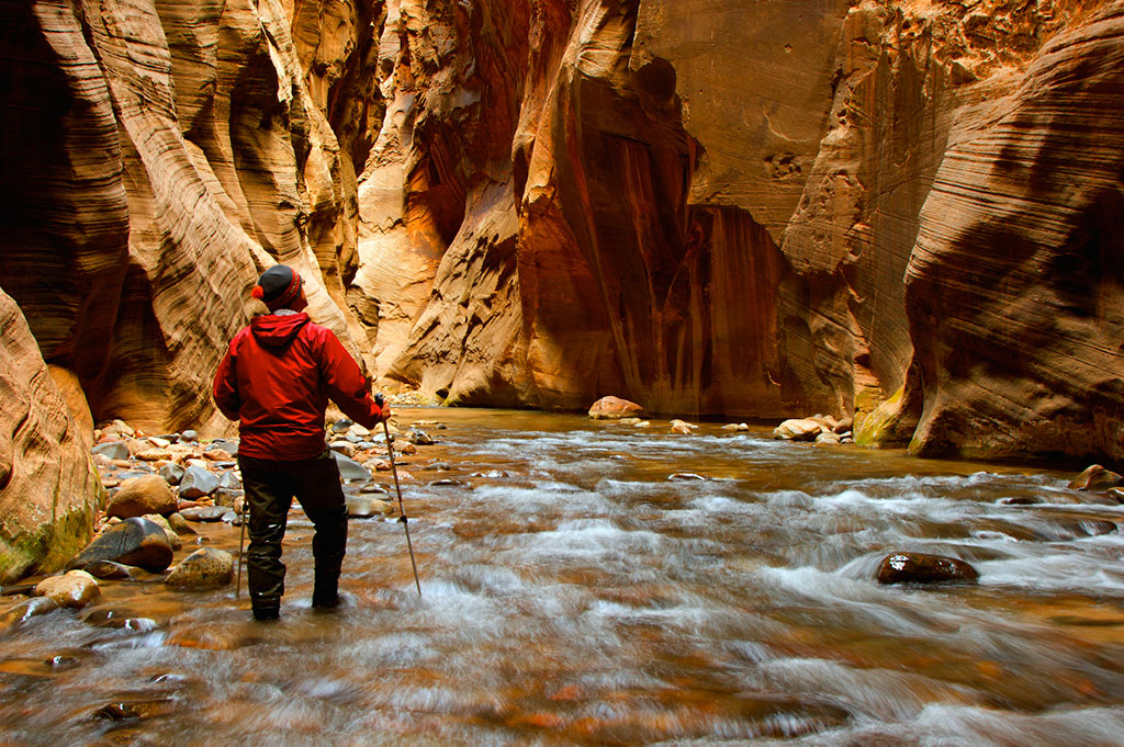 hiker standing in water with canyons on either side