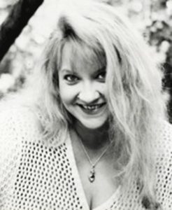 Close-up black and white photo of author Cerridwen Greenleaf smiling at the camera
