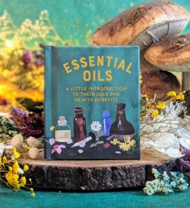 Photo of "Essential Oils" standing on a short log surrounded by mushrooms and flowers