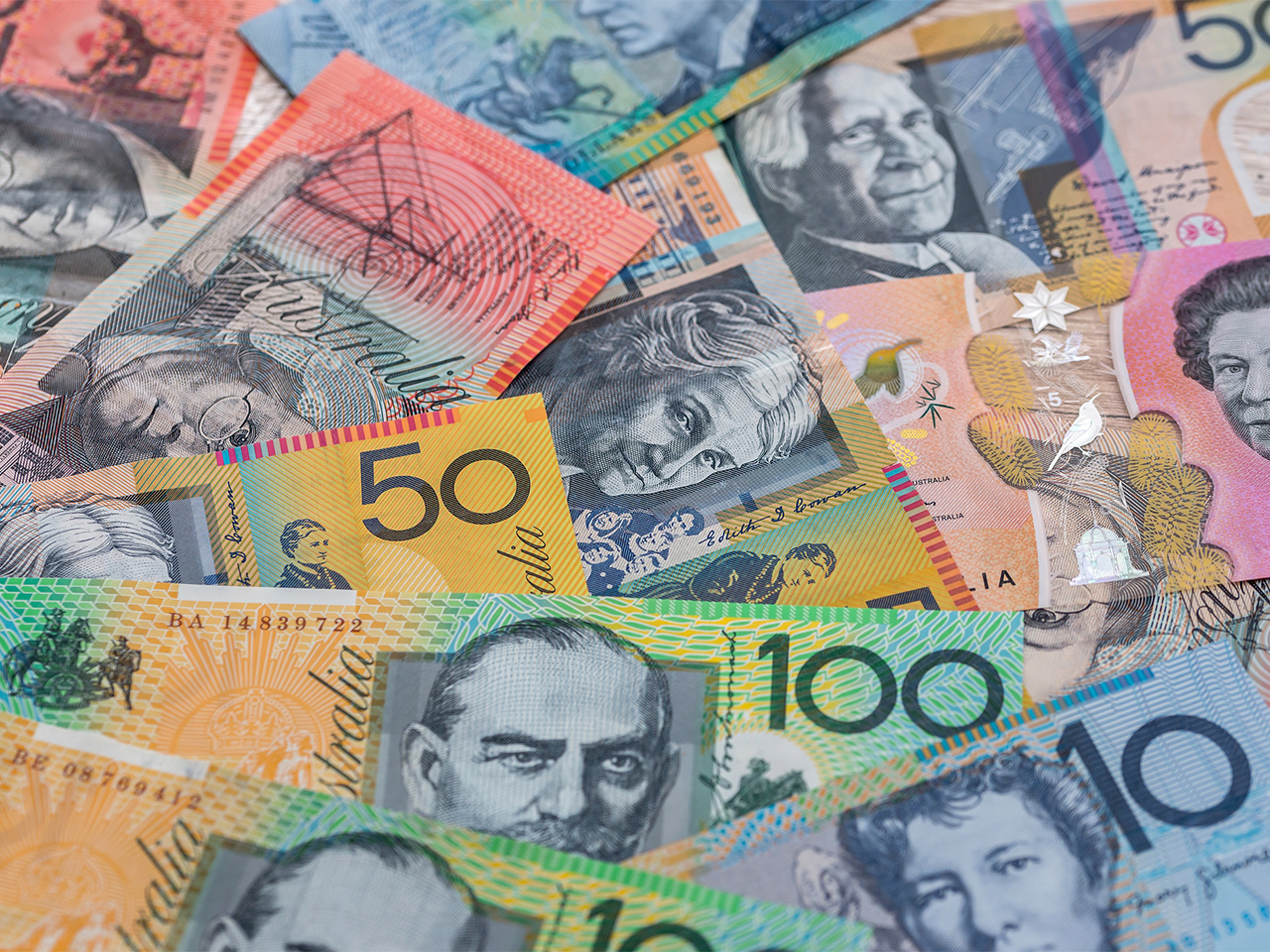 Australian bank notes in a range of denominations scattered on a surface.