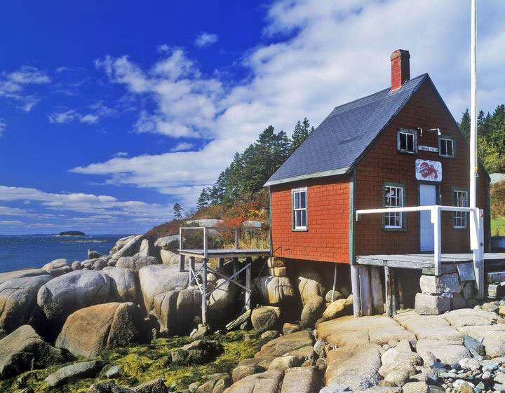 A red lobster house on the rocky coast on a summer day.