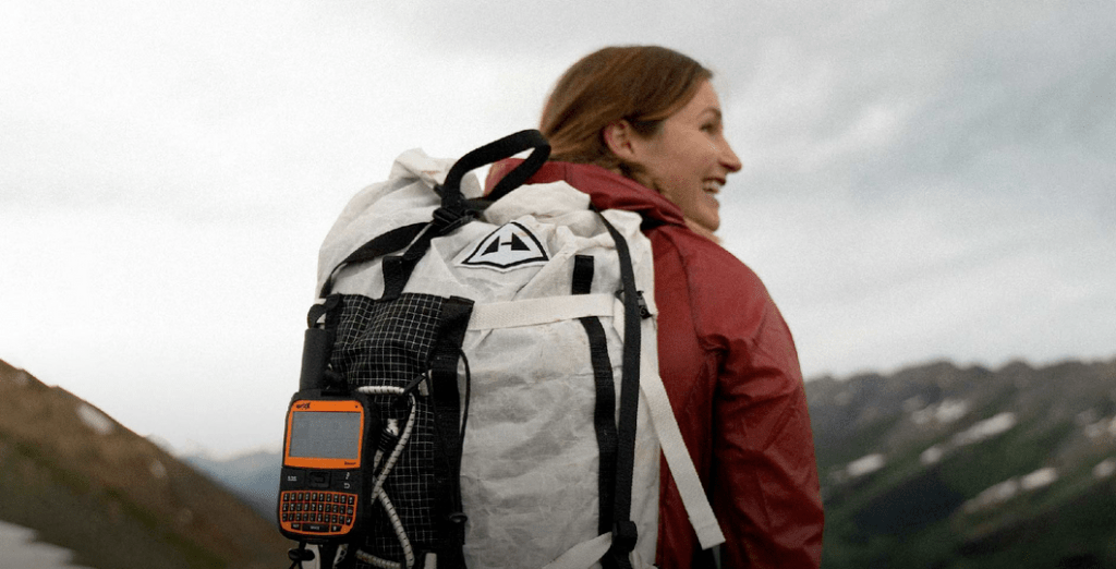 Woman hiker with a Spot messenger hanging on her backpack