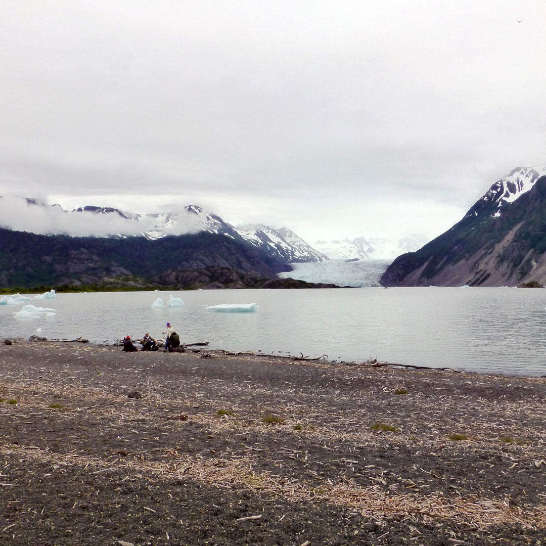 hikers sitting on the beach near the Grewingk Glacier lake