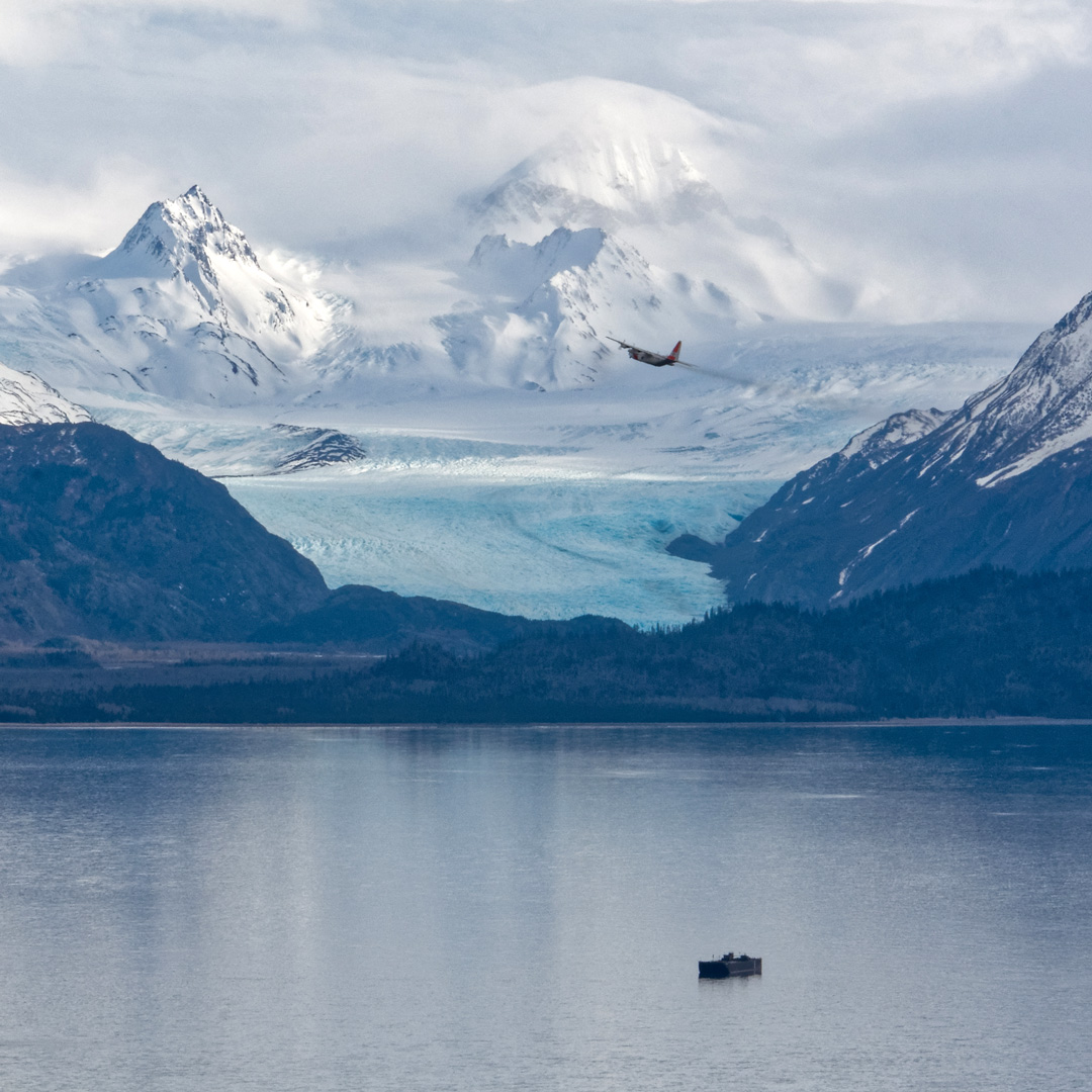 a boat in kachemak bay with snowy mountains and a glacier in the background