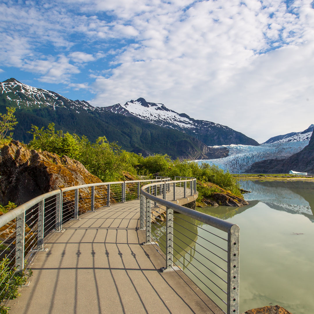 a concrete pathway leading to a glacier and mountains