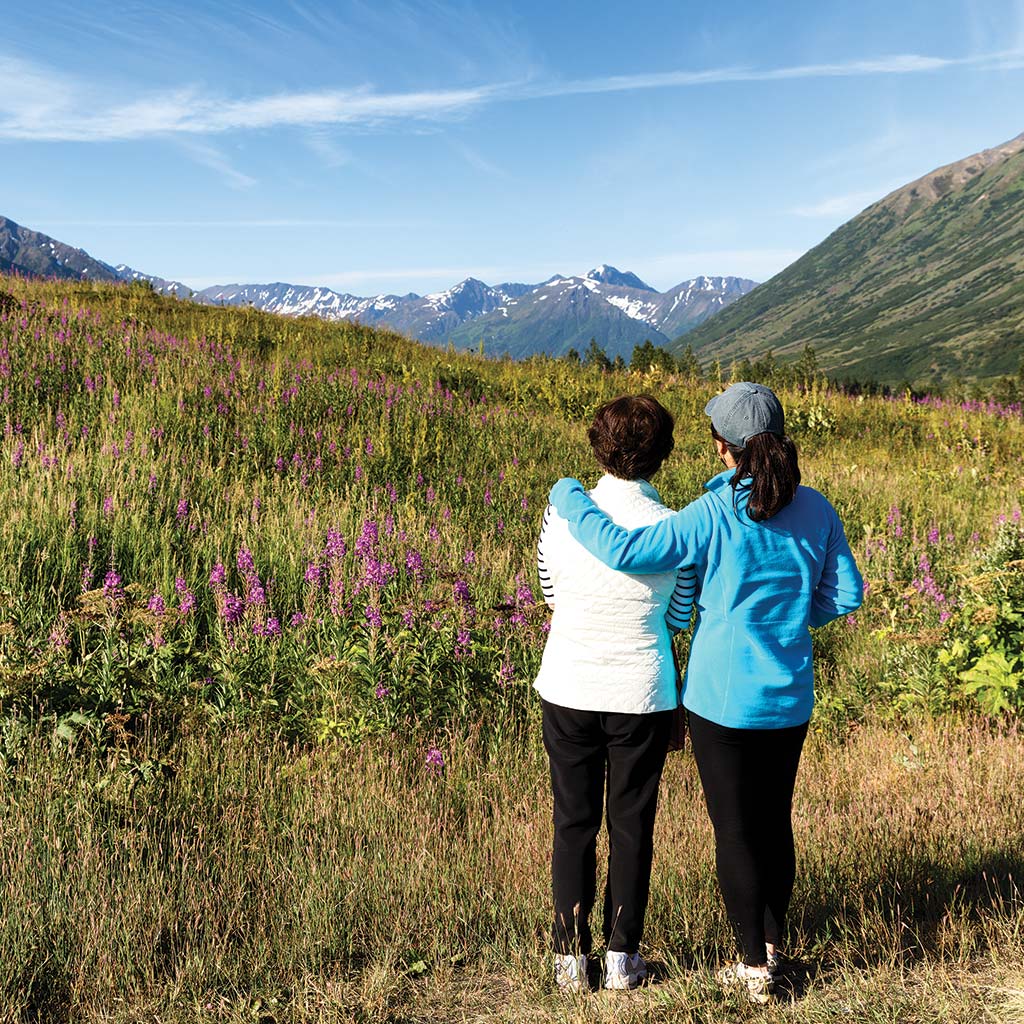 Two women stand together and admire the Denali landscape