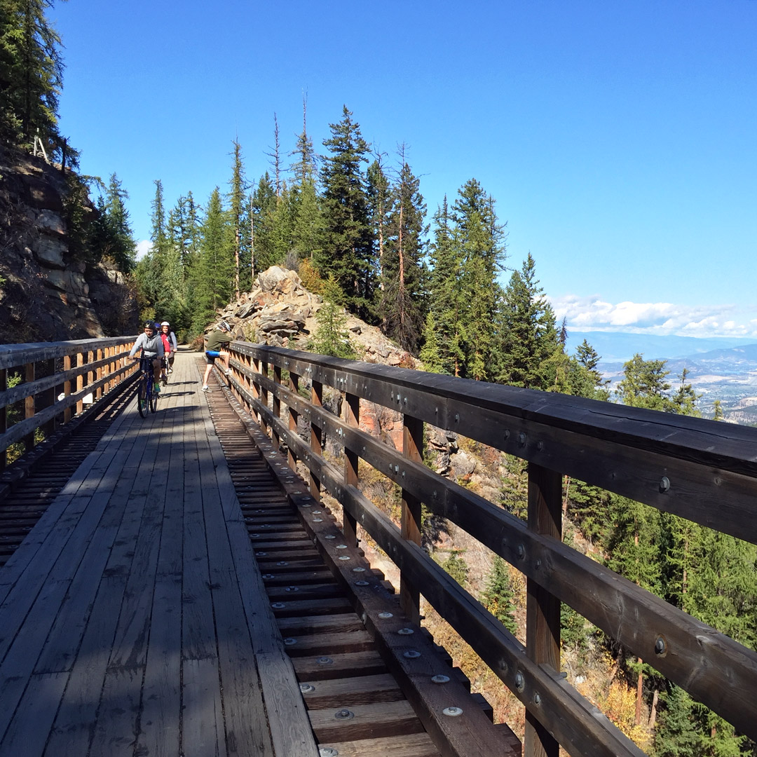 cyclists riding bikes along kettle valley railway with views of British Columbia