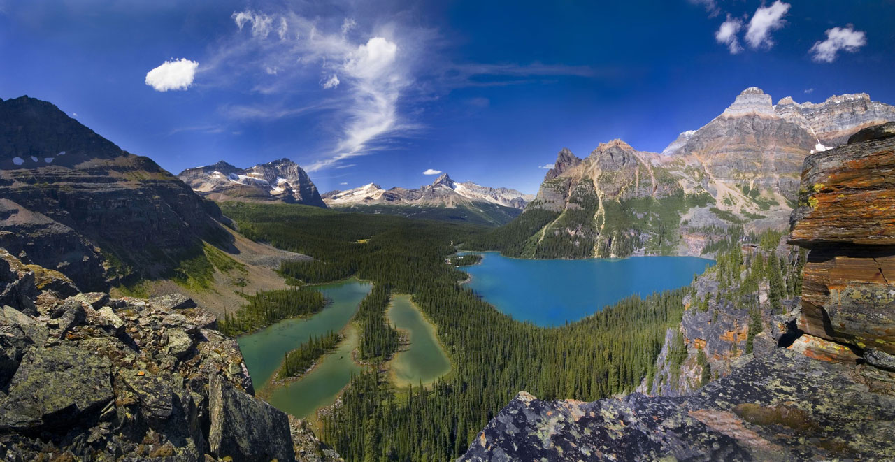 Panoramic view of an alpine lake surrounded by mountain peaks.