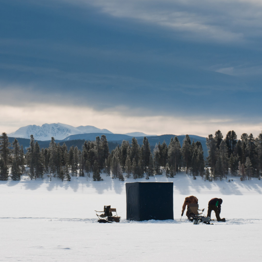 two people out on a frozen over lake in Colorado going fishing