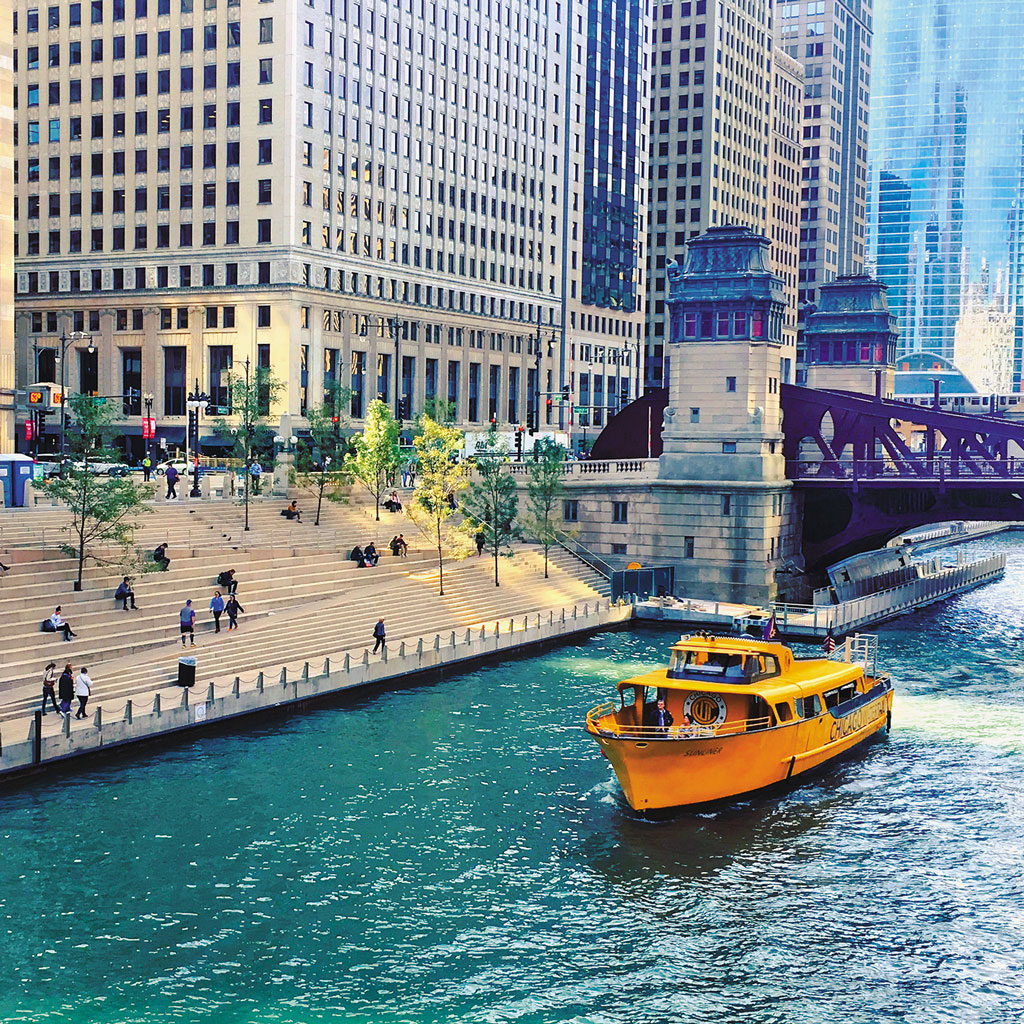 a yellow boat on the river in Chicago surrounded by tall buildings