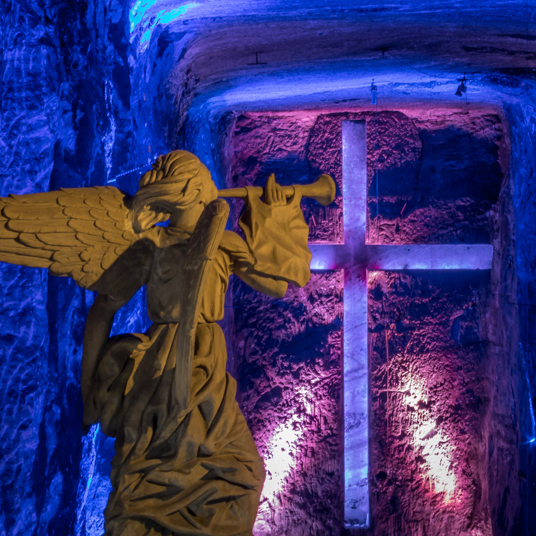 angel statue and cross lit in blue and pink in the Catedral de Sal