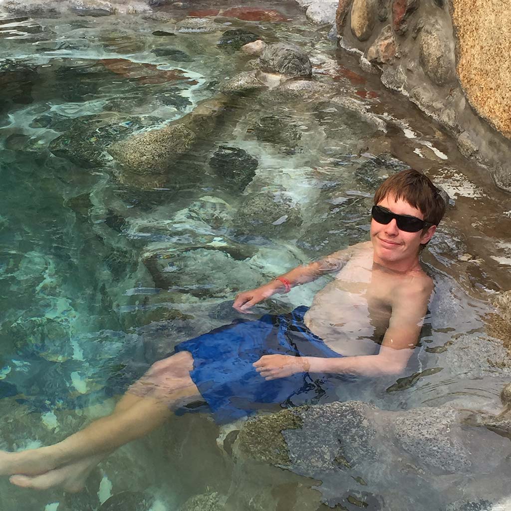 A young man hangs out with sunglasses on in a hot spring pool