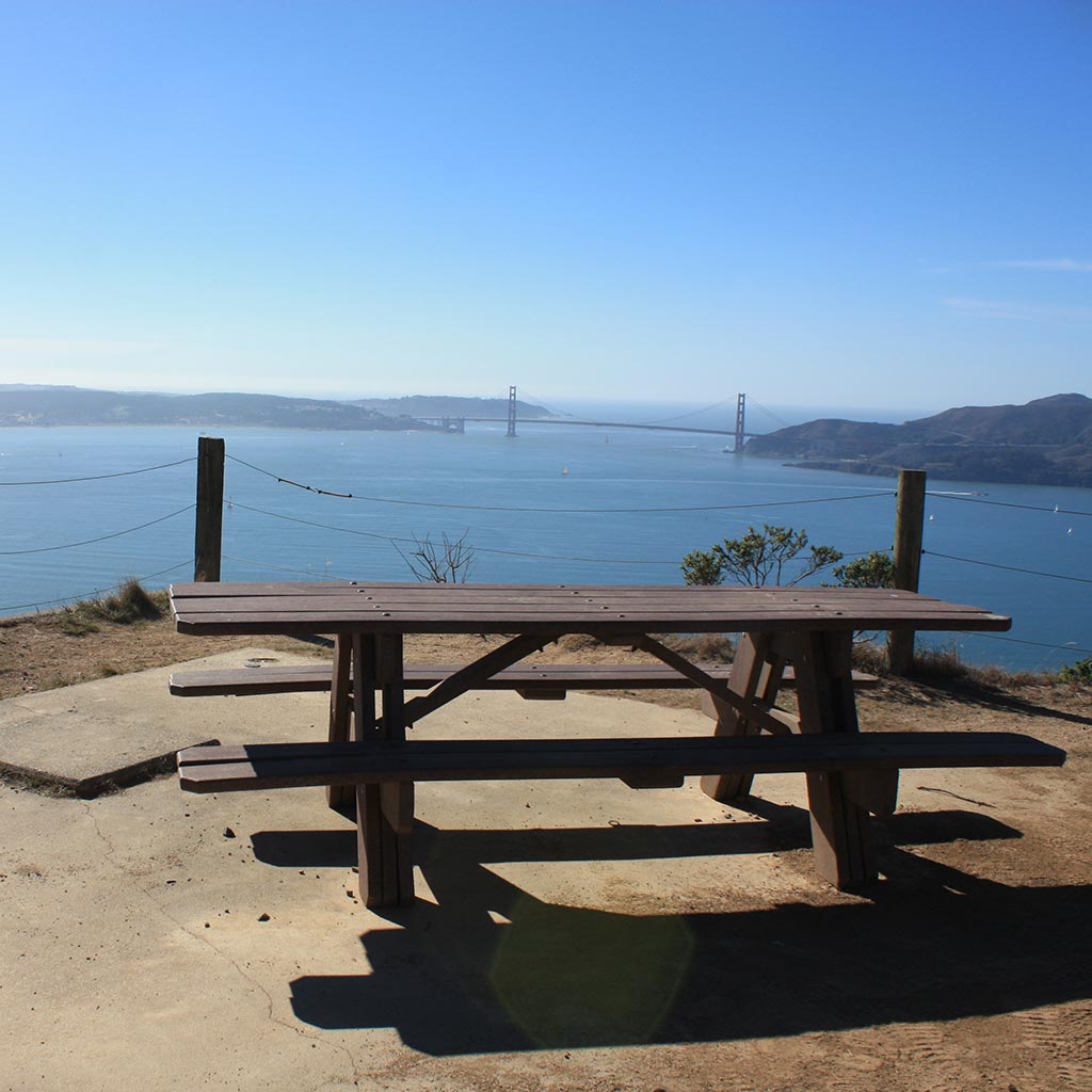 A picnic bench overlooks a stunning vista of the Bay with the Golden Gate bridge looming in the background. Taken at Angel Island State Park campsite.