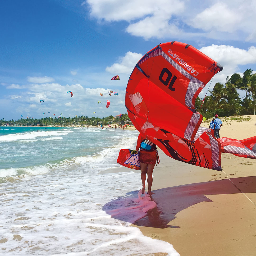 a surfer standing in the waves next to a kite