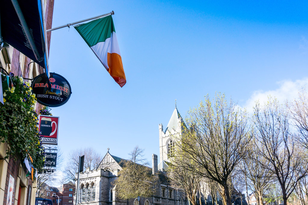 an irish flag flies along a street lined with pubs