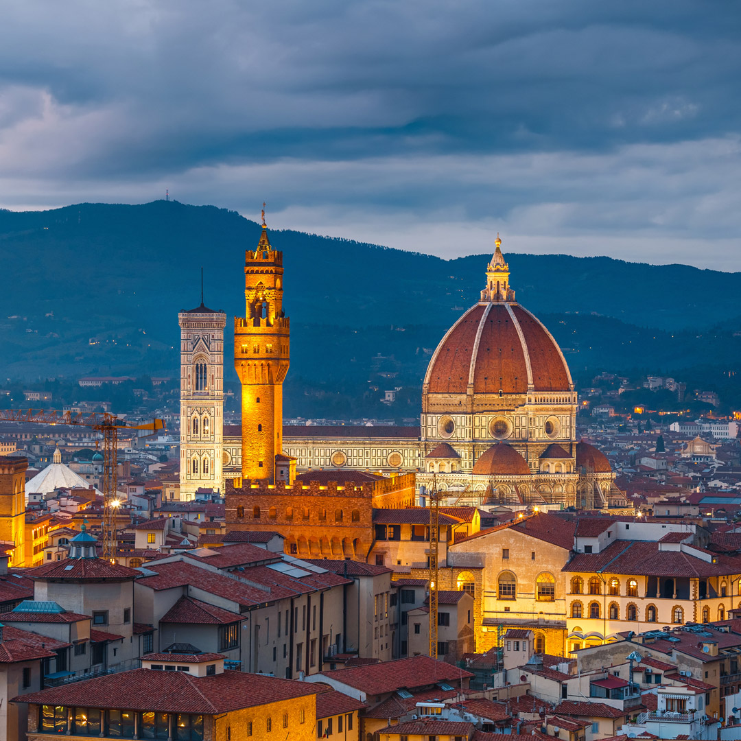Rooftops and Duomo of Florence lit by city lights at dusk