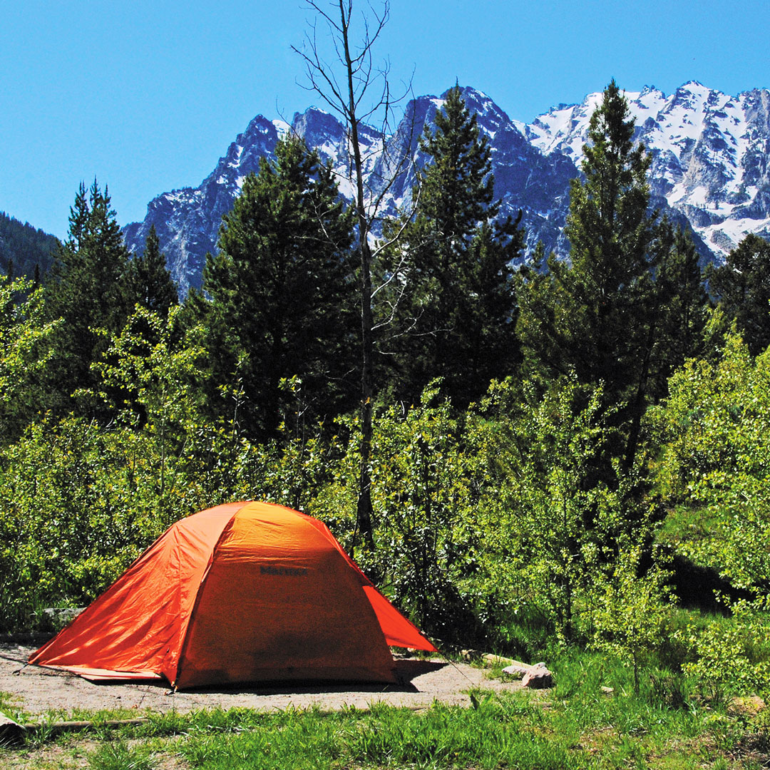 orange tent camping with a view of the Teton mountains