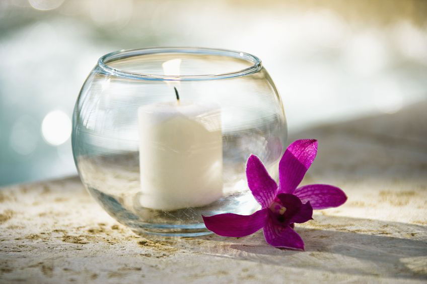 An orchid and a lit candle at a spa experience.