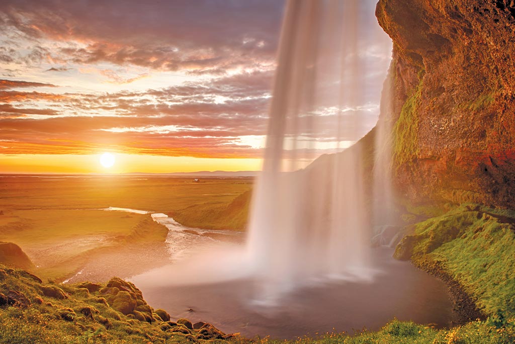 Two of Iceland's natural wonders–the midnight sun and waterfalls. Photo © Phyletto/Dreamstime.