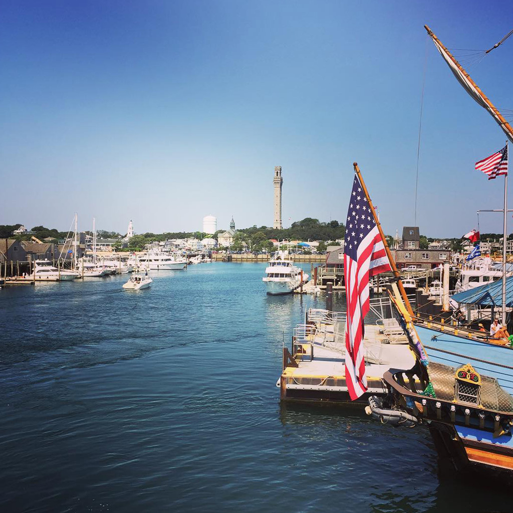 american flag waves with a backdrop of Provincetown MA