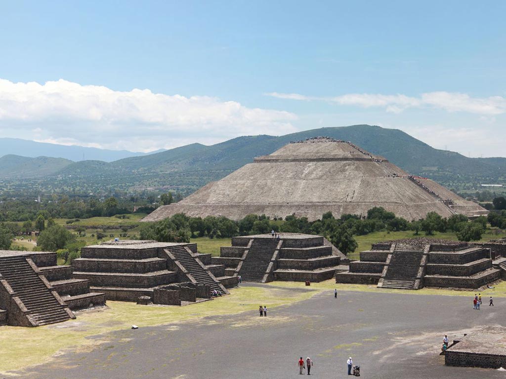 view from above of the ruins of Teotihuacan with mountains in the background