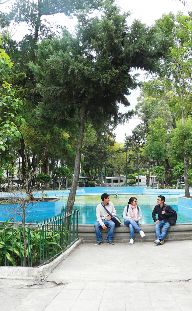 three people sitting on the edge of a fountain