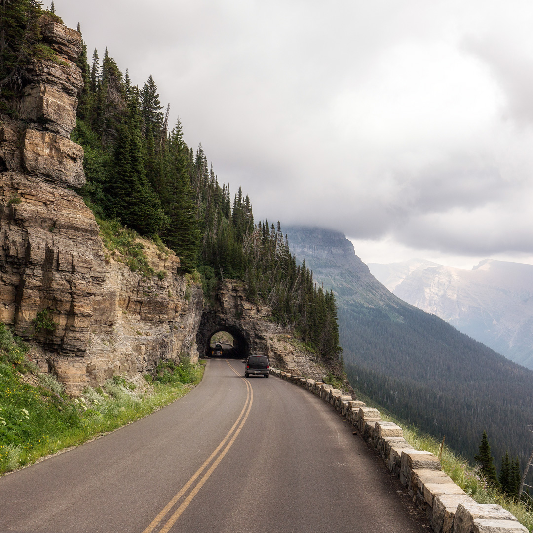 car approaching a tunnel through mountain on a cloudy day in Montana