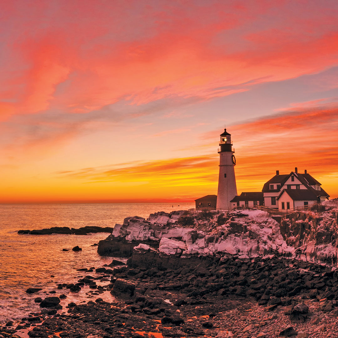 bright pink and orange sky behind Portland Head Lighthouse
