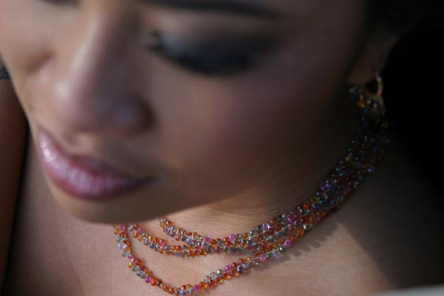 Photograph of a polynesian woman wearing a delicate necklace made of three strands of beaded gemstones.