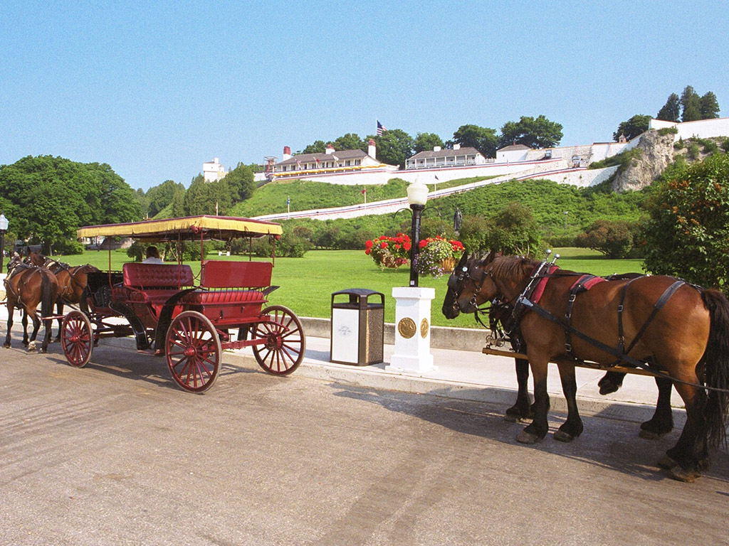 horse-drawn carriages sit in front of fort mackinac