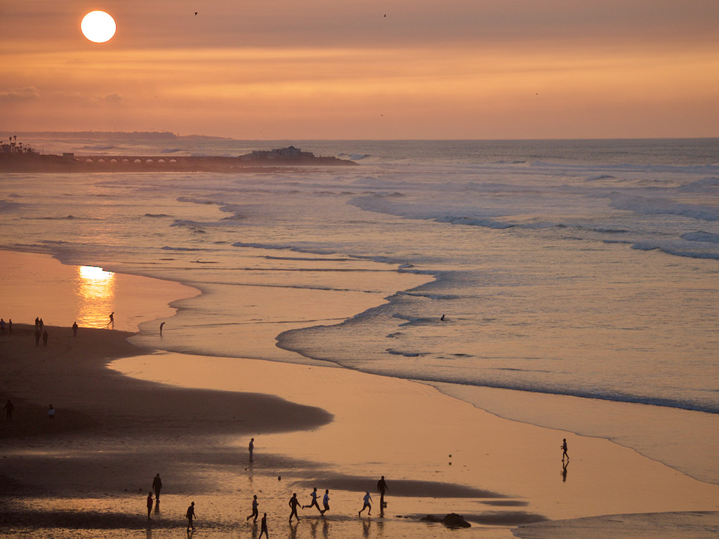 waves roll up onto the beach at sunset in Casablanca