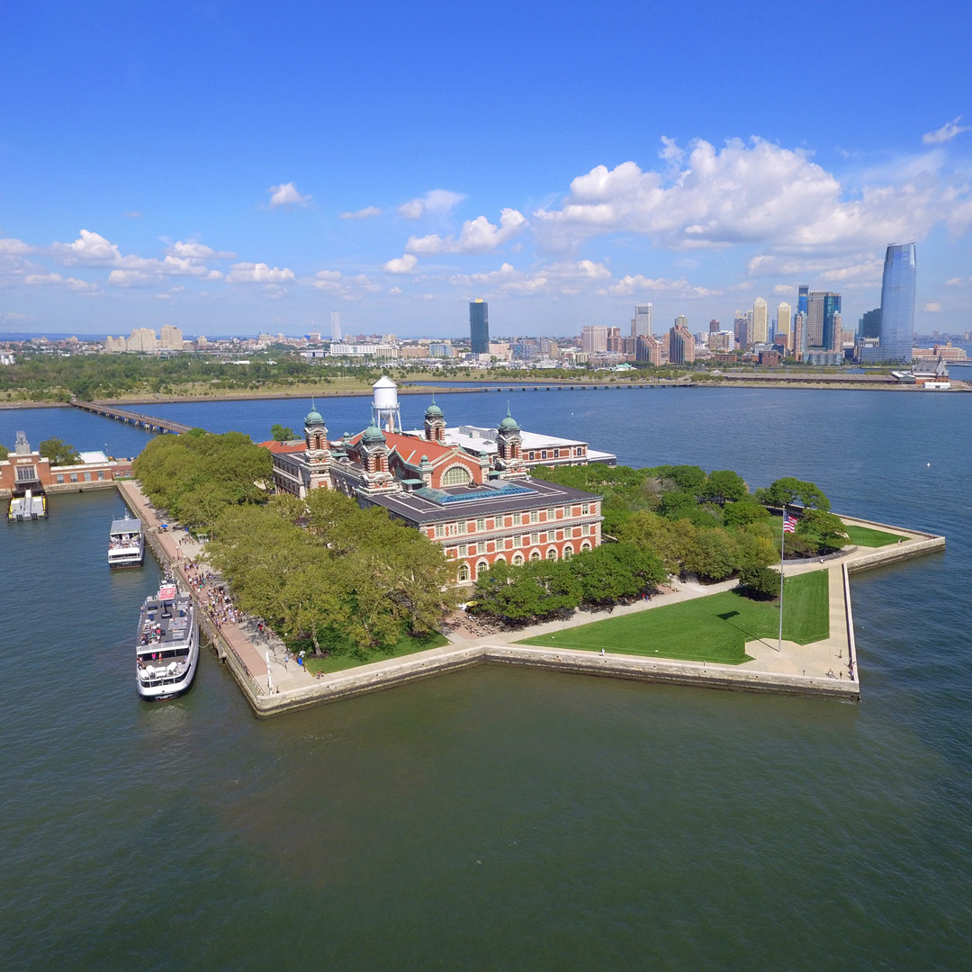 view of Ellis Island surrounded by water with the New York City skyline in the distance