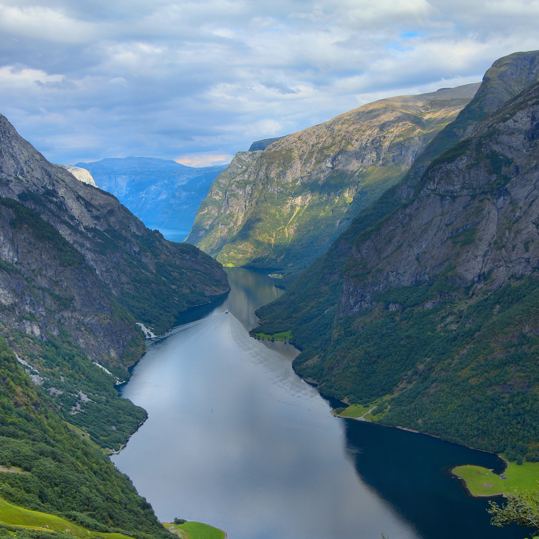 a ship sails through Naeroyfjord in Norway