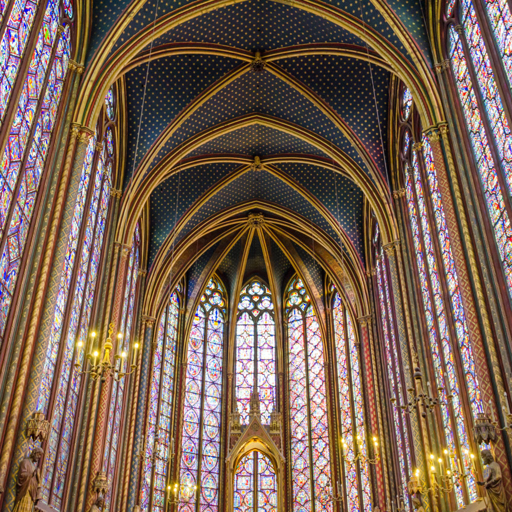 light shines through the stained glass windows inside of Sainte Chapelle