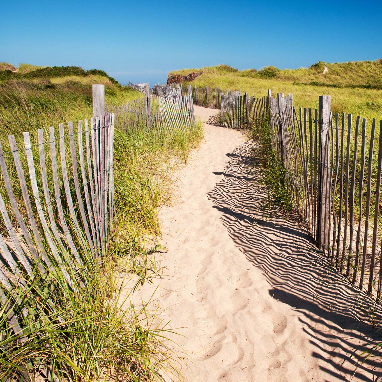 A sandy path lined by a wooden fence at Block Island's Crescent Beach.
