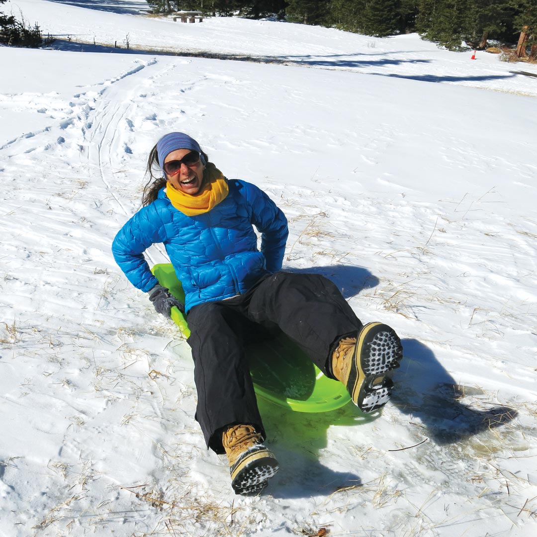 woman laughing on a sled in snow
