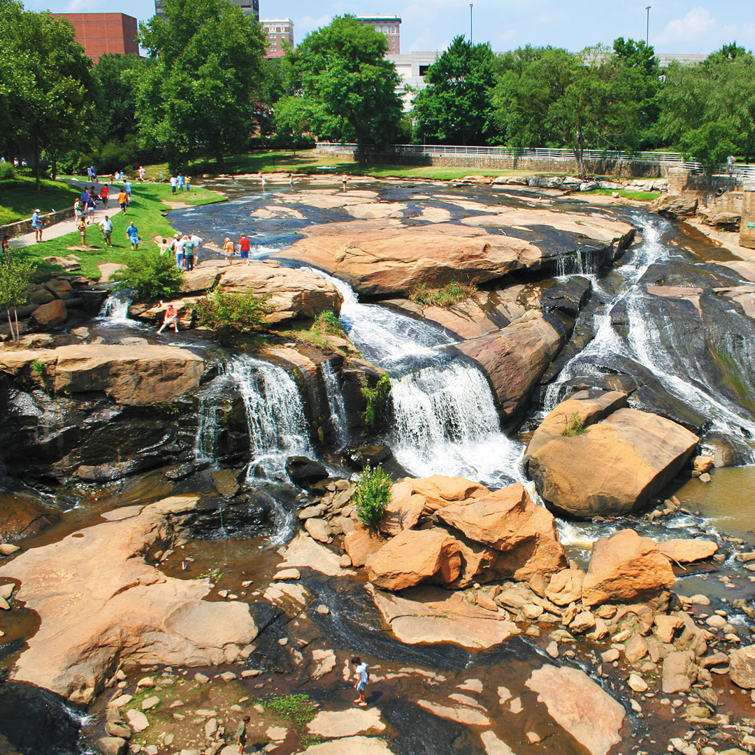 people playing in the water at Falls Park on the Reedy River