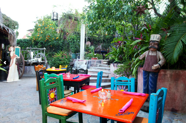 Set in a courtyard, chairs and tables are painted in different vibrant colors.