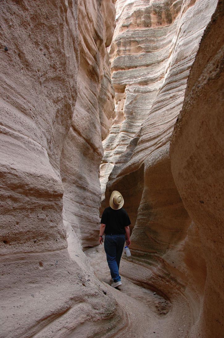 Hiker explores a slot canyon at Kasha-Katuwe Tent Rocks National Monument, New Mexico.