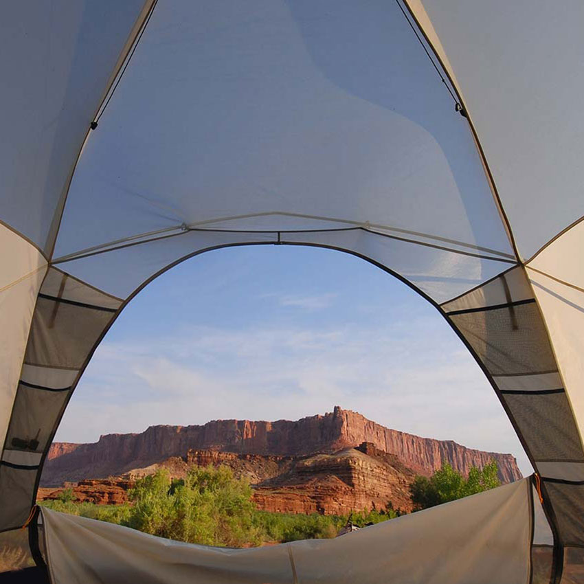 inside a tent, looking out at the scenic vista of Canyonlands through unzipped tent door