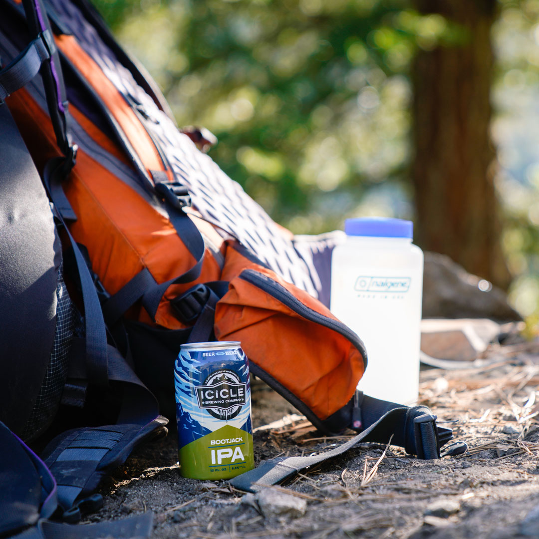 a can of beer propped up against a backpack