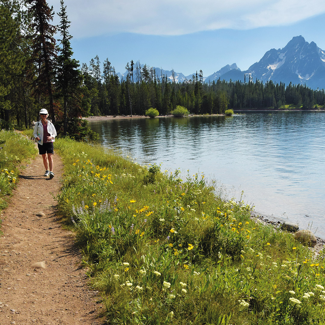 woman walking on a trail next to a lake in Wyoming