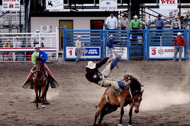 A rider being bucked off the back of a horse at the Cody Nite Rodeo.