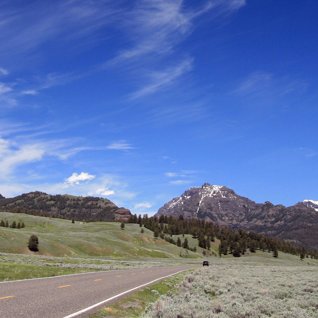 blue sky over a road leading toward the mountains in Yellowstone
